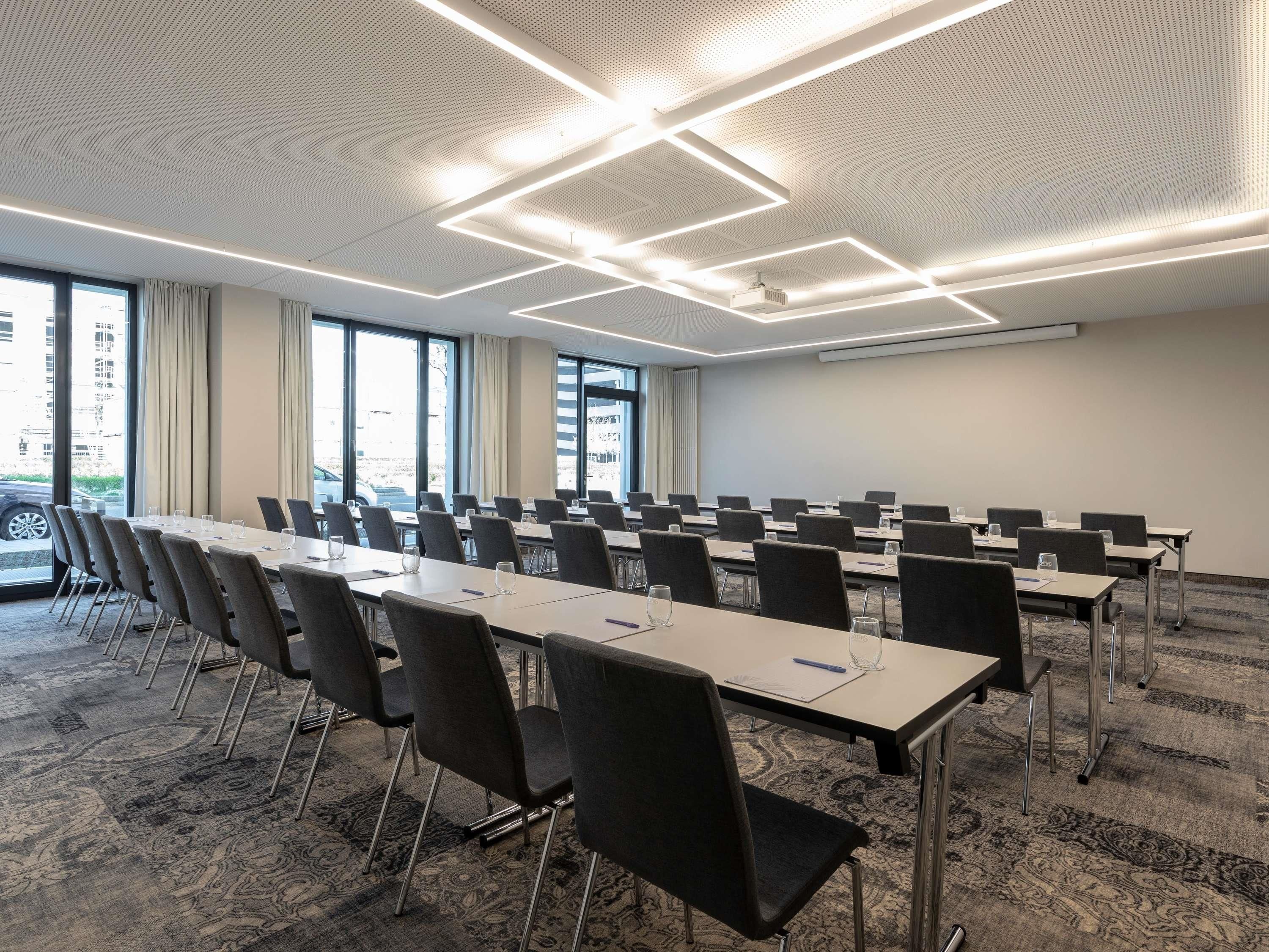 Une salle de conférence équipée d’une longue table, de chaises et d’un écran de projection.
