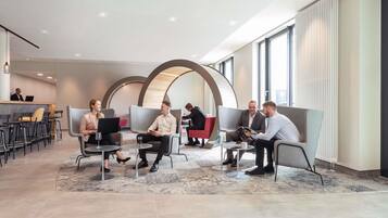 A modern lobby with seating areas, a reception desk, and large windows.
