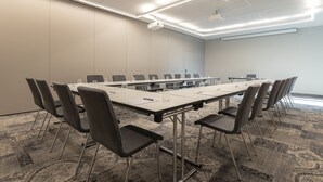 Une salle de conférence équipée d’une longue table, de chaises et d’un projecteur.