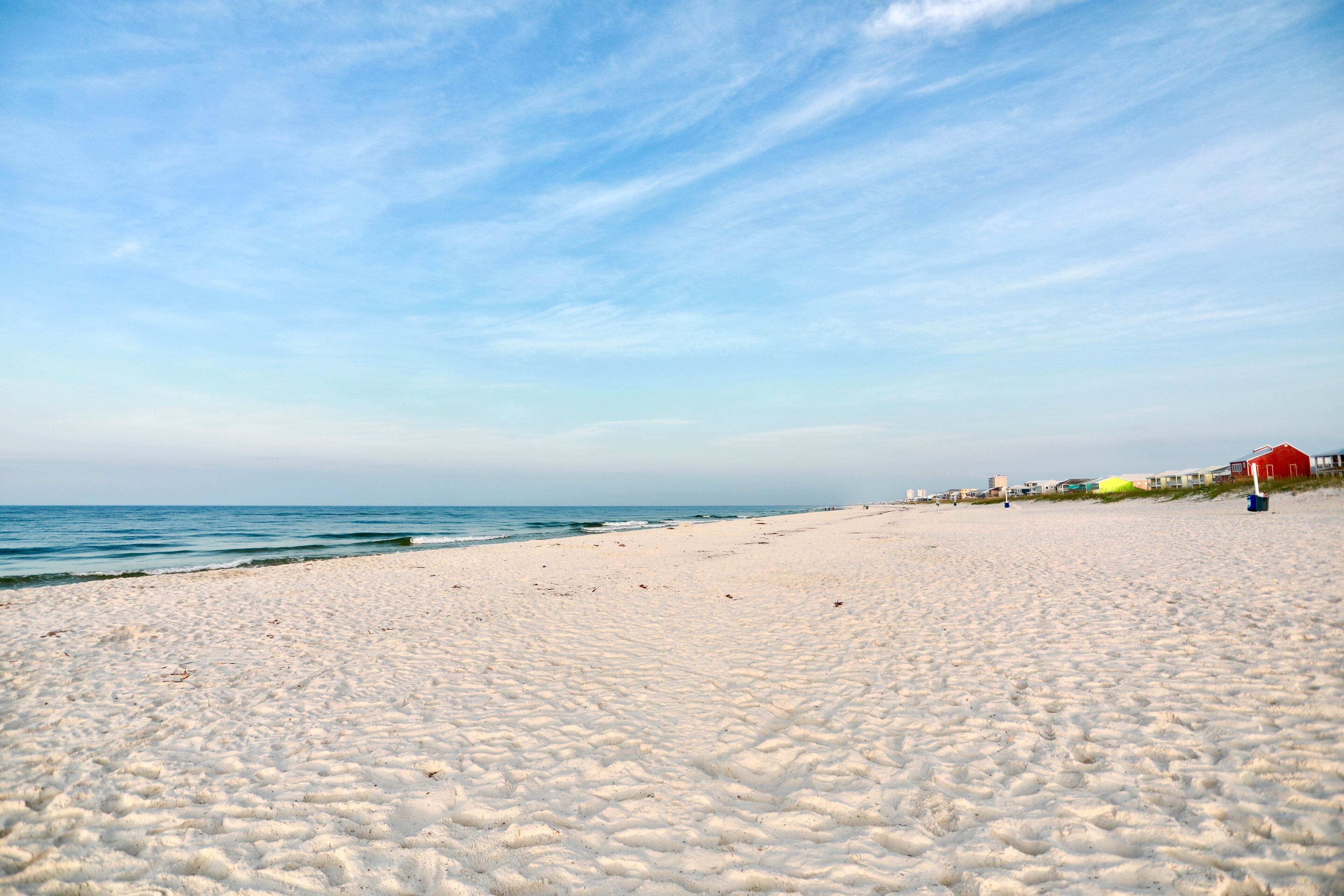 A beach with white sand and a clear blue sky.