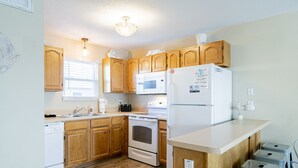Una cocina con armarios de madera, un refrigerador blanco, un microondas y una estufa.