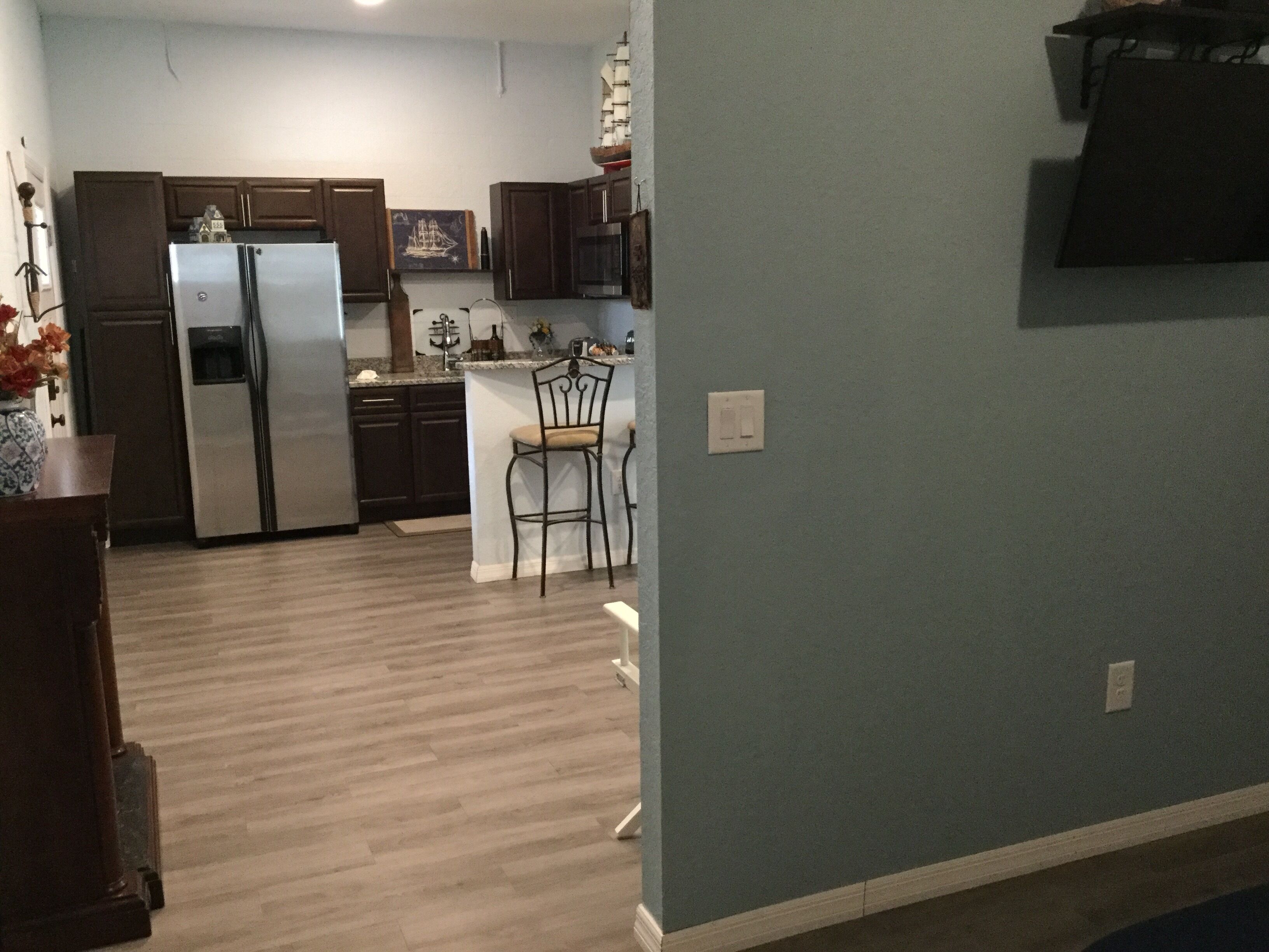 A kitchen with a refrigerator, microwave, and wooden cabinets.
