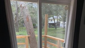 A room with a large sliding glass door leading to an outdoor wooden deck with a metal railing.