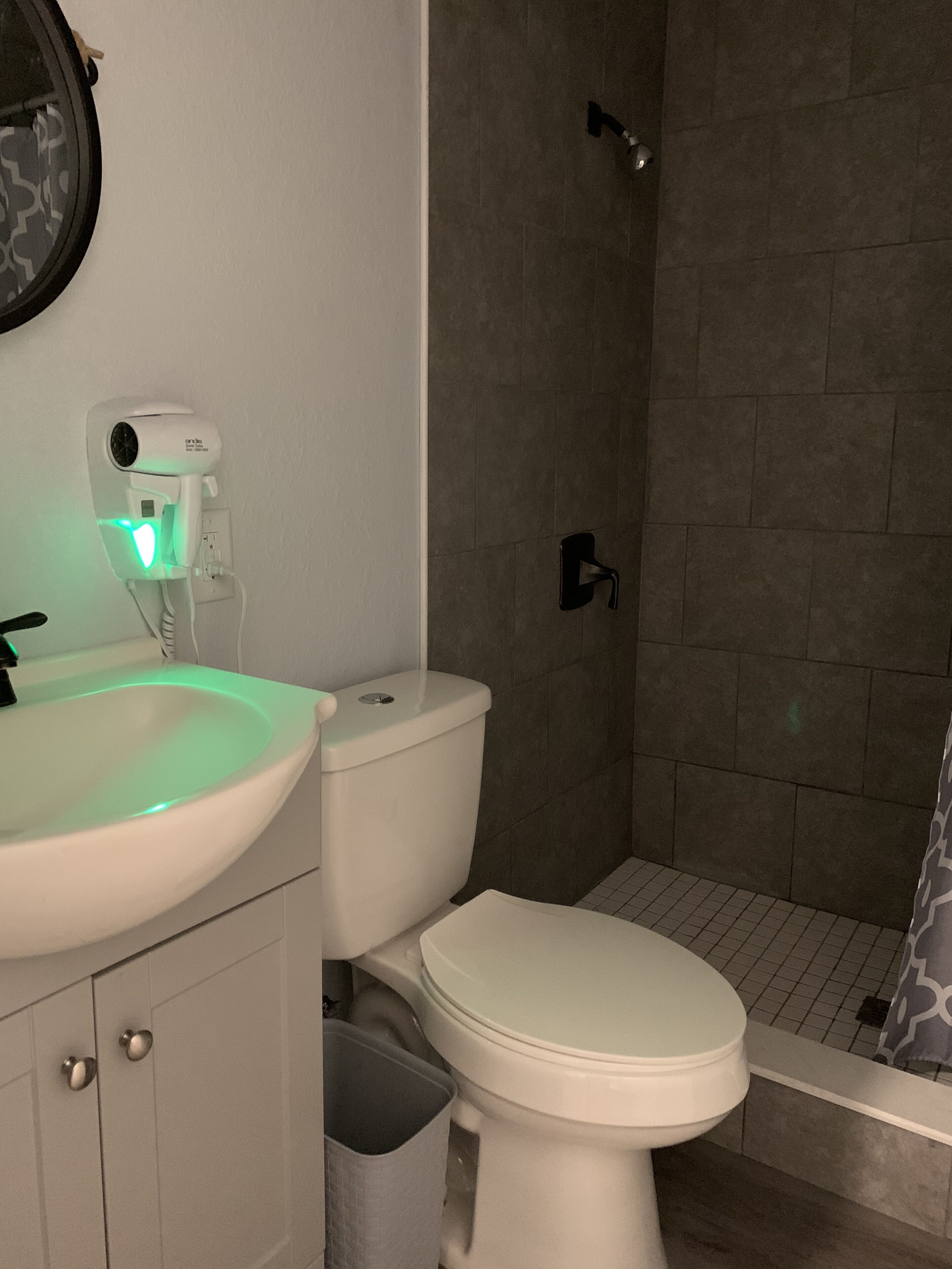 Een badkamer met een wit wastafel, toilet en douche.