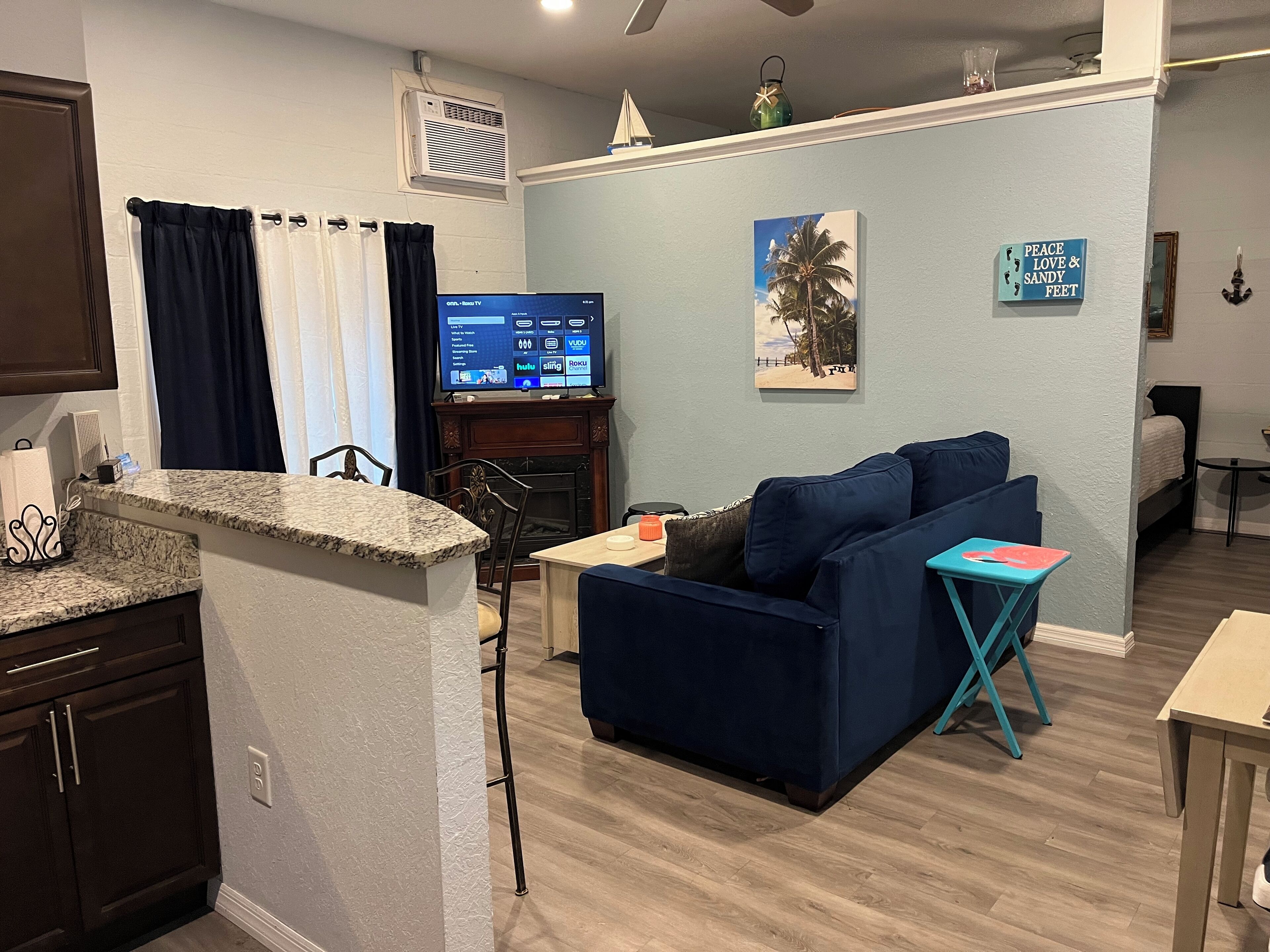 A living room with a dark blue sofa, a small table, and a TV displaying channel options.