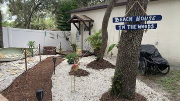 Enjoy a tranquil backyard retreat with a boat, bird sculpture, and grill, perfect for outdoor activities.