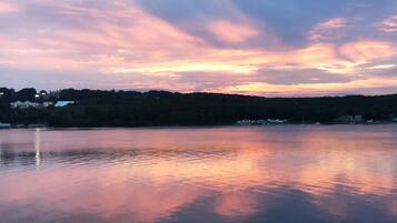 A calm lake at sunset with a distant shoreline and buildings.