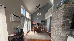 A spacious kitchen with a stone accent wall, a dining area with a chandelier, and a ceiling fan. - Riverfront Home with a View! (Groton)