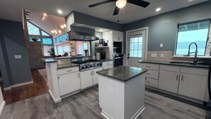 A modern kitchen with a central island, built-in appliances, and a view of the outdoors. - Riverfront Home with a View! (Groton)
