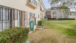 Ein Gebäude mit zahlreichen Fenstern, ein Garten mit Gartenschlauch und einem gepflegten Rasen.