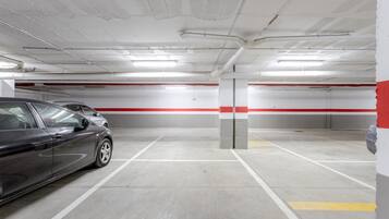 Un parcheggio sotterraneo con pavimenti in cemento, pareti bianche e rosse e luci fluorescenti.