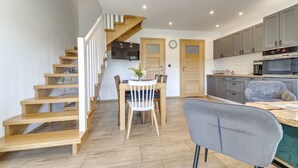 A modern kitchen with grey cabinets, a built-in oven, and a grey upholstered chair. - Siglanów by Interhome (Wisla)