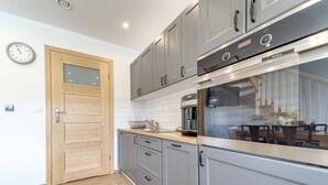 A modern kitchen with grey cabinets, a wooden door, and a built-in oven. - Siglanów by Interhome (Wisla)