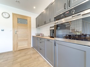 Een koelkast, een oven, een vaatwasser, kookgerei, borden en bestek