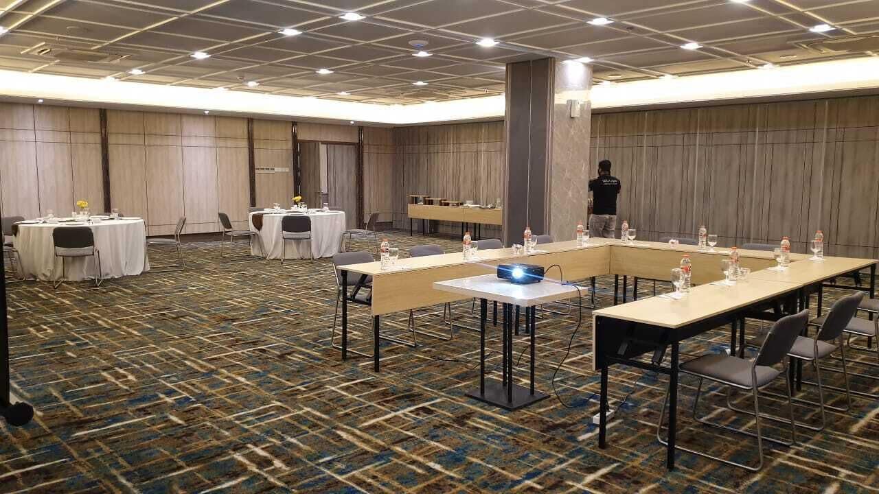 A conference room with long tables, chairs, and a projector.