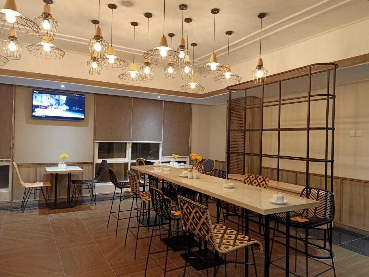 A conference room with a long table, multiple chairs, and hanging pendant lights.