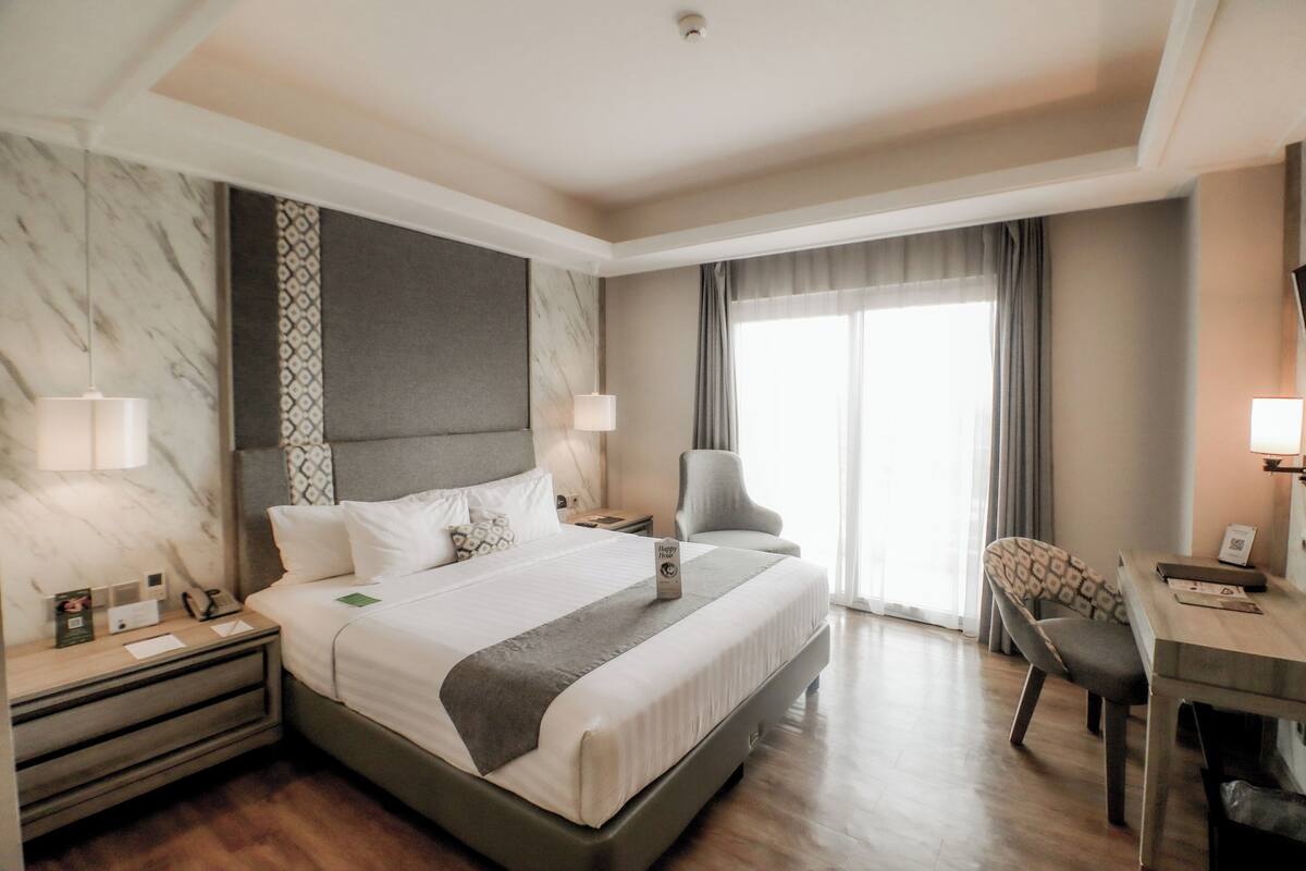 A hotel room with a large bed, bedside tables, a desk, and a chair.