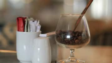 Et glas med kaffebønner og en kanelstang på et bord.