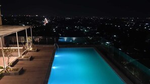 A rooftop pool with a city view at night. - Zigna Kampung Batik (Surakarta)