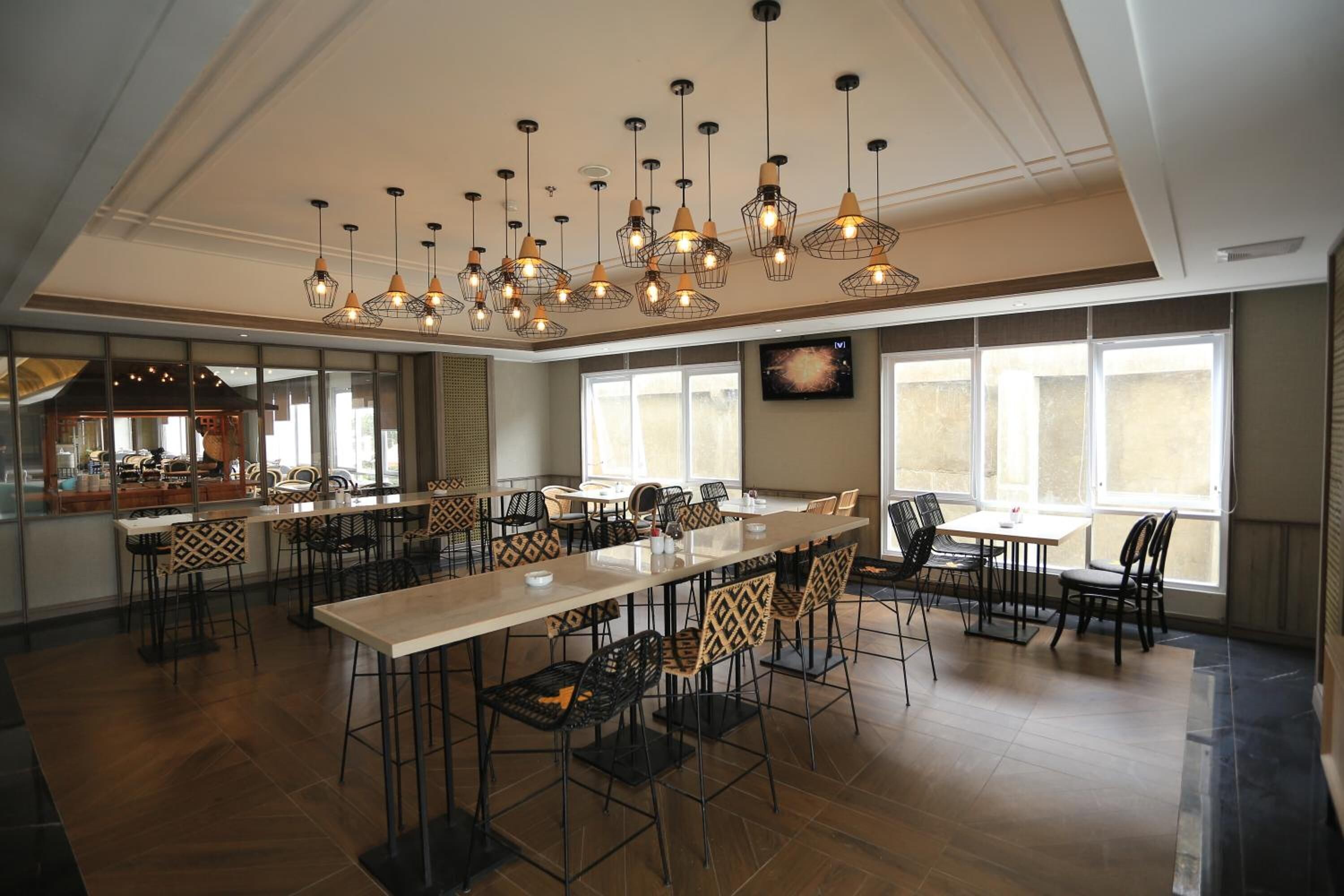 Un comedor amplio con una mesa larga y sillas, iluminación colgante y ventanas grandes que dejan entrar luz natural.