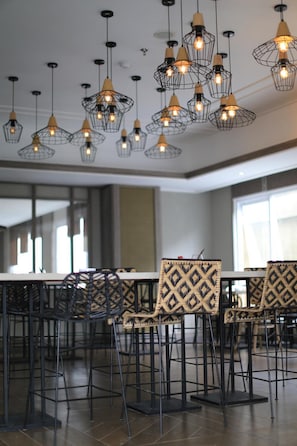 A dining area with multiple tables and chairs, featuring geometric patterned upholstery and black metal chairs.