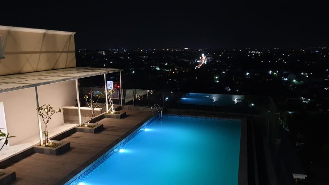 Une piscine sur le toit offrant une vue sur la ville la nuit.