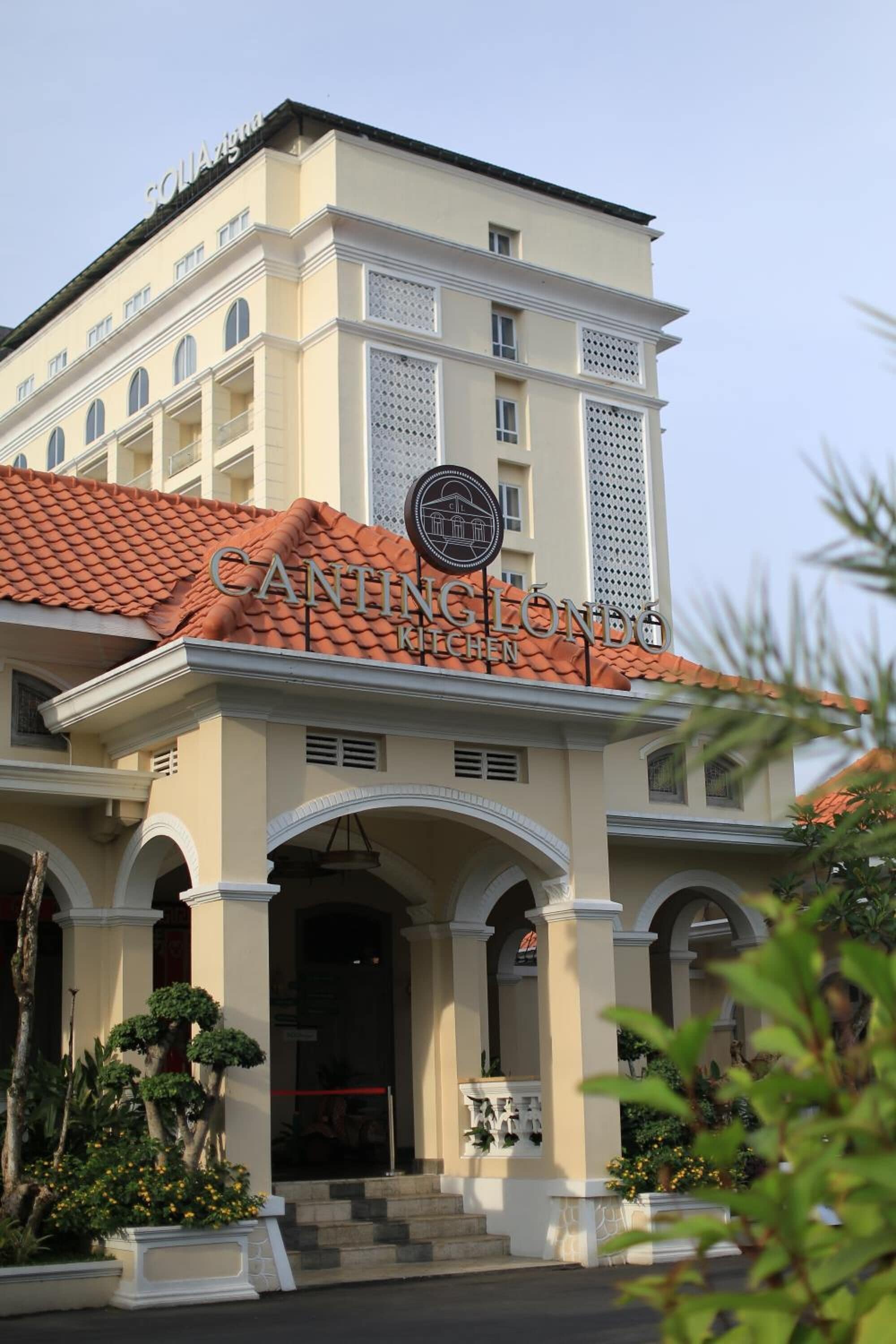 Um hotel com estilo arquitetônico clássico, apresentando uma entrada imponente com arcos e telhado de azulejos.