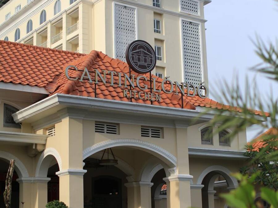 Um hotel com estilo arquitetônico clássico, apresentando uma entrada imponente com arcos e telhado de azulejos.