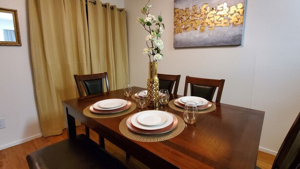 Une table à manger dressée avec des assiettes, des verres et un vase de fleurs.