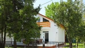 A modern two-story house with a white exterior and orange accents, surrounded by lush greenery and a metal fence. - Vacation home Pixie by Interhome (Balatonoszod)