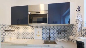 A modern kitchen with white cabinets, stainless steel appliances, and geometric patterned backsplash. - Vacation home Pixie by Interhome (Balatonoszod)
