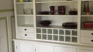 A kitchen with white cabinets, a green wall, and various kitchenware. - Ferienwohnung Immergrün (Görisried)