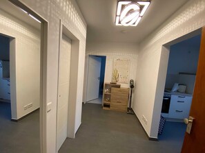 Ein Flur mit einer Leuchte, einem Holzschrank und einer Wand mit einem Poster.