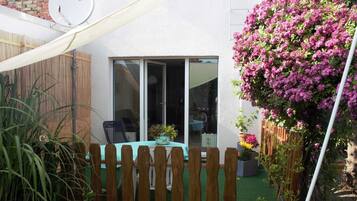 A patio with a wooden fence, a table with chairs, and a potted plant.