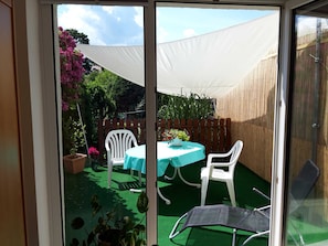 A patio with a table and chairs, surrounded by a wooden fence and potted plants.