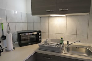 A kitchen with a microwave, toaster, sink, and dish rack.