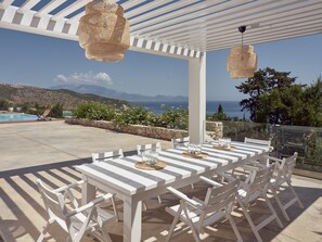 A covered outdoor dining area with a pool and scenic mountain views.