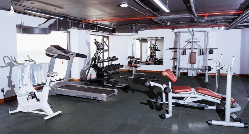 Uma academia com aparelhos de cardio, equipamentos de musculação e espelhos.