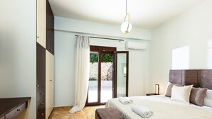 Une chambre à coucher comprenant un lit, un banc, une armoire, une porte-fenêtre coulissante et un appareil de climatisation.
