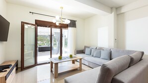 Un salon moderne avec un canapé, une table basse et un téléviseur posé sur un meuble en bois.