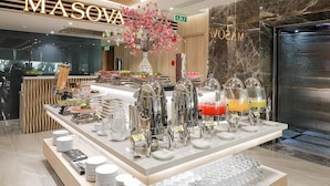 A buffet area with a variety of food and drink options, including a fruit display and beverage dispensers. - Masova Hotel (Nha Trang)