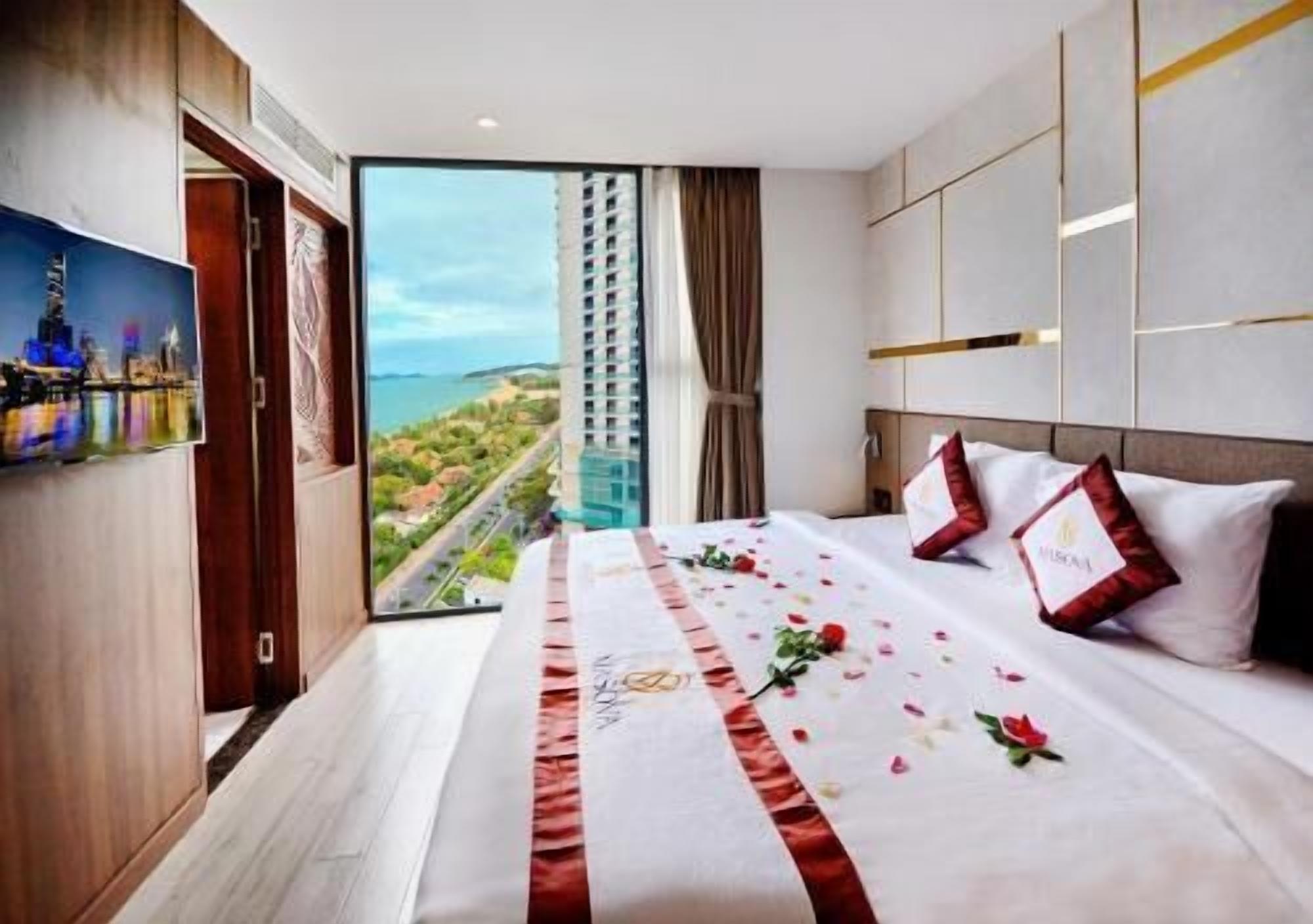 A hotel room with a large bed, a view of a cityscape, and a balcony.