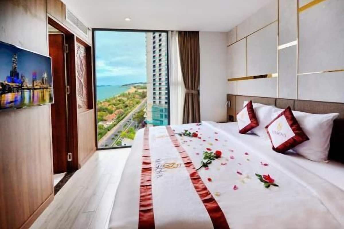 Une chambre d’hôtel avec un grand lit, une vue sur la ville et un balcon.