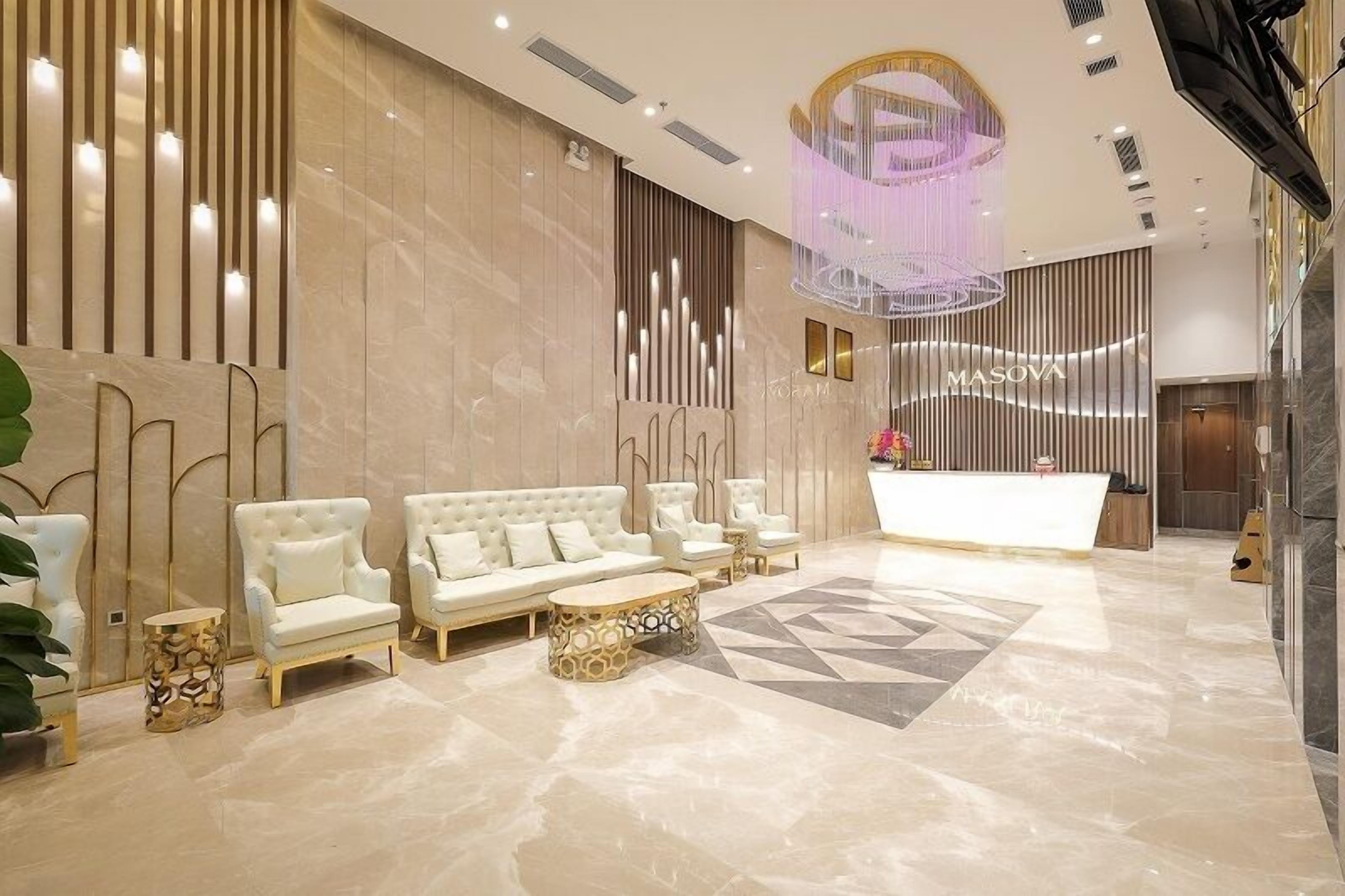 Een moderne lobby met een receptiebalie, comfortabele zitplaatsen en een sierlijke kroonluchter.