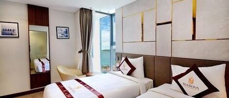 A hotel room with two beds, a large window, a mirror, and a view of the city.