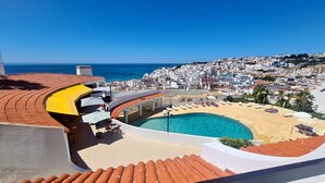 A rooftop pool with a clear view of the sea and a cityscape in the background.