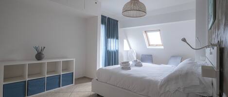 Ein modernes Hotelzimmer mit einem großen Bett, einem Schreibtisch, einem Stuhl, einer Lampe und Deckenleuchte.