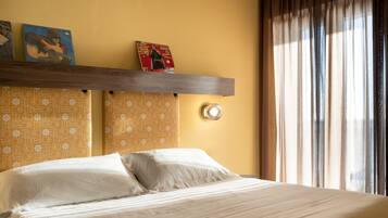 Una habitación de hotel con cama, un estante decorado y una ventana con cortinas.
