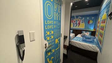 A hotel room with a bed, a wall-mounted phone, and a door with a 'LOVE IT' sign.