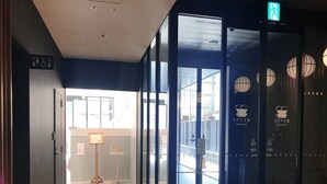 A hallway with a glass door leading to a room with a view of the outside. There is a sign indicating a restroom and a wheelchair symbol. - Henn na Hotel Premier Nara (Nara)